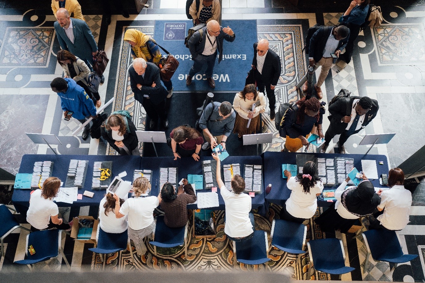Image shows foyer of Exam Schools with delegates arriving to the reception desk to find their name badge