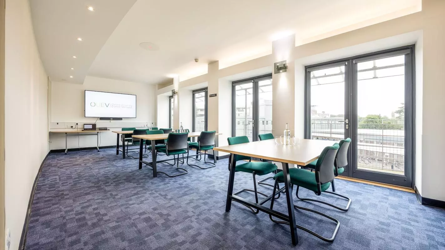 Meeting Room with three square tables each with four green chairs stationed at each