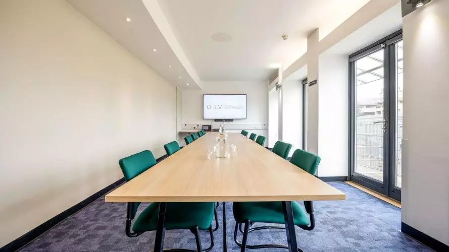 Long rectangular table with green chairs around the outside 