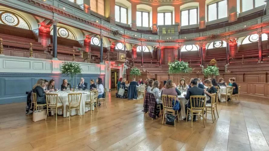 People sat at round dinner tables in the Sheldonian Theatre auditorium