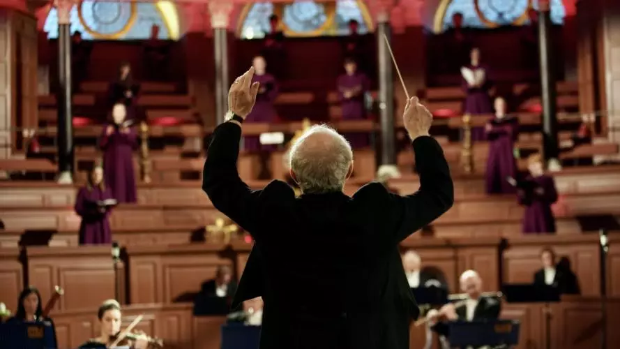 conductor leading the orchestra in the Sheldonian Theatre
