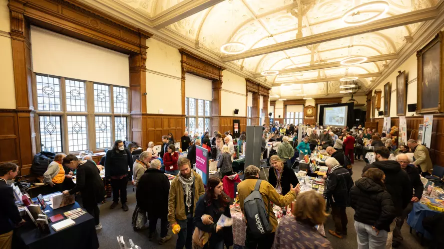 people walking around a fair at Exam Schools, looking at a variety of stalls and having conversations with staff.
