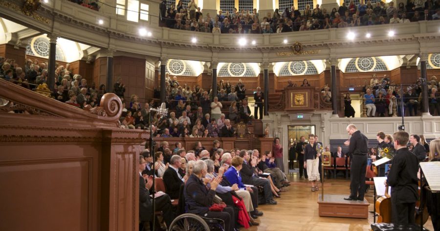This is a picture of an audience sat listening to an orchestra at the Sheldonian Theatre