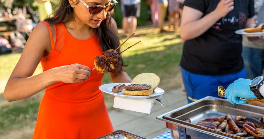 This is an image of a girl helping herself to a burger from a buffet station while at a summer party at Osler House